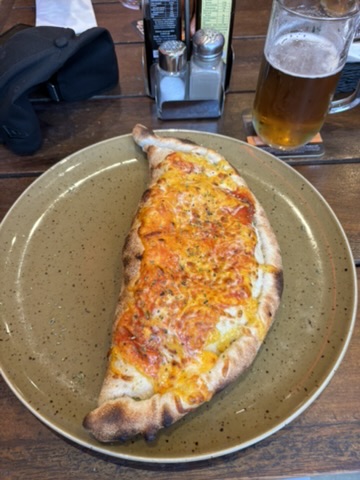 Frisch gebackene Calzone auf einem Teller neben einem kühlen Bier
